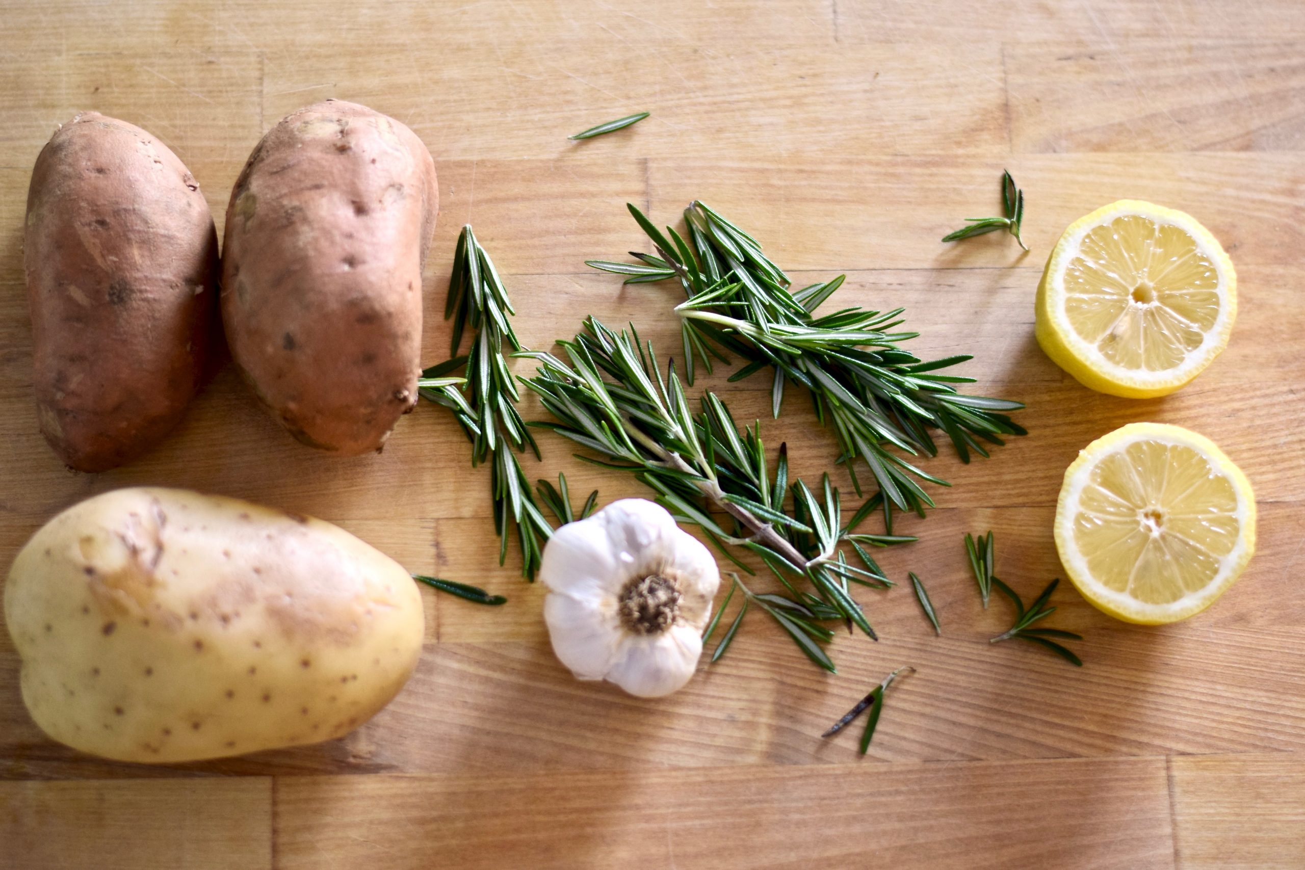 potatoes, garlic, rosemary and lemon halves on countertop