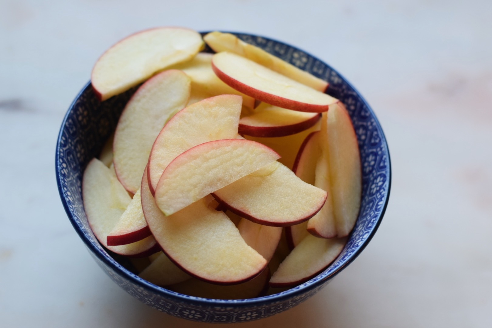 thinly sliced apples in blue bowl