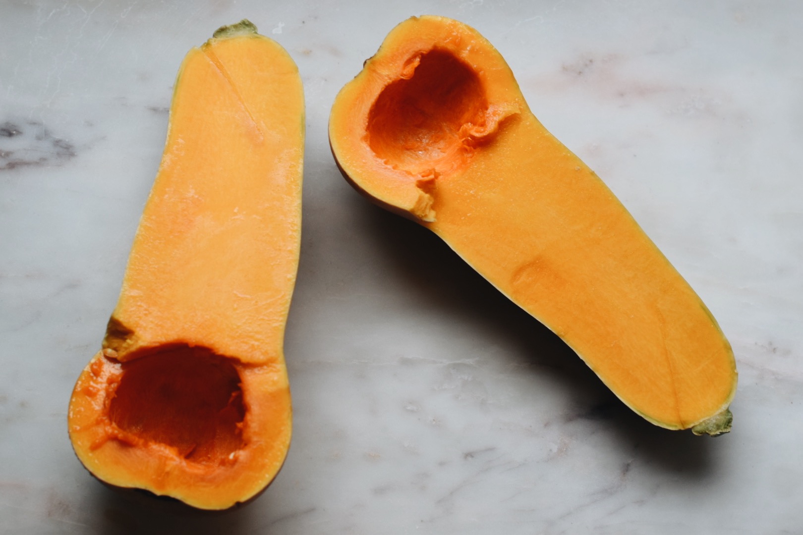 butternut squash cut in half on a white surface