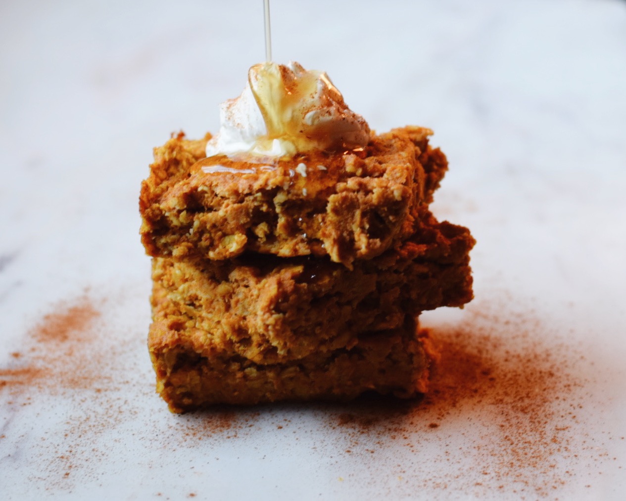 stacked pumpkin spice baked oatmeal with yogurt and maple syrup drizzle