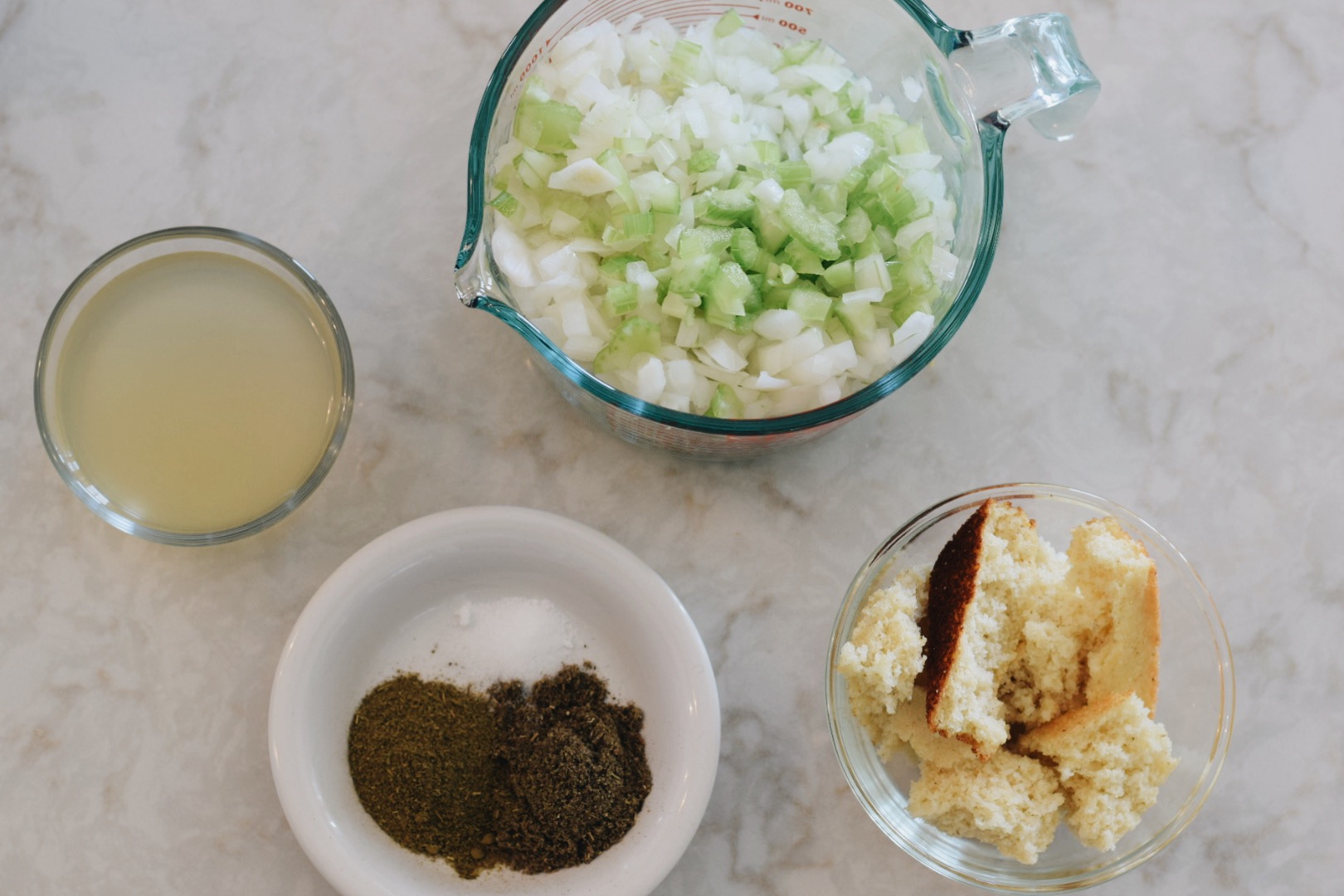 spices, celery, onions, broth and cornbread in separate bowls 