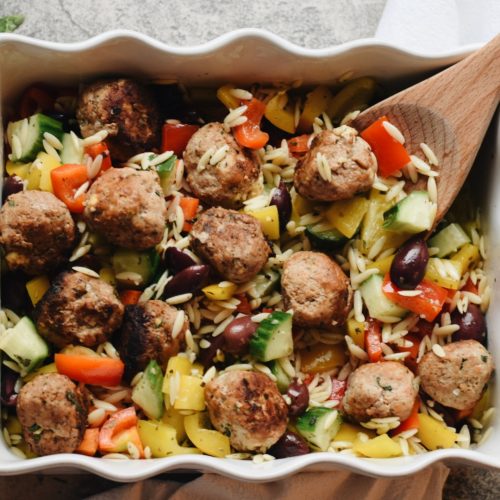meatballs on a bed of orzo in a white serving dish