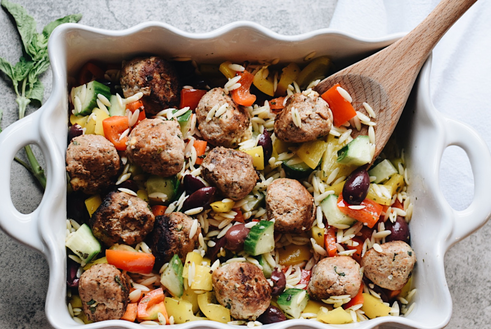 meatballs on a bed of orzo in a white serving dish