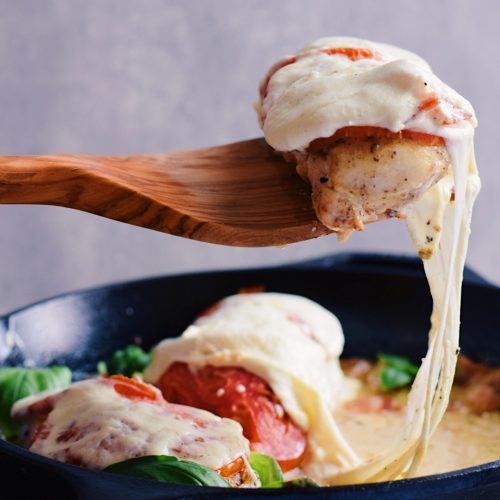 caprese chicken on a spatula over a skillet