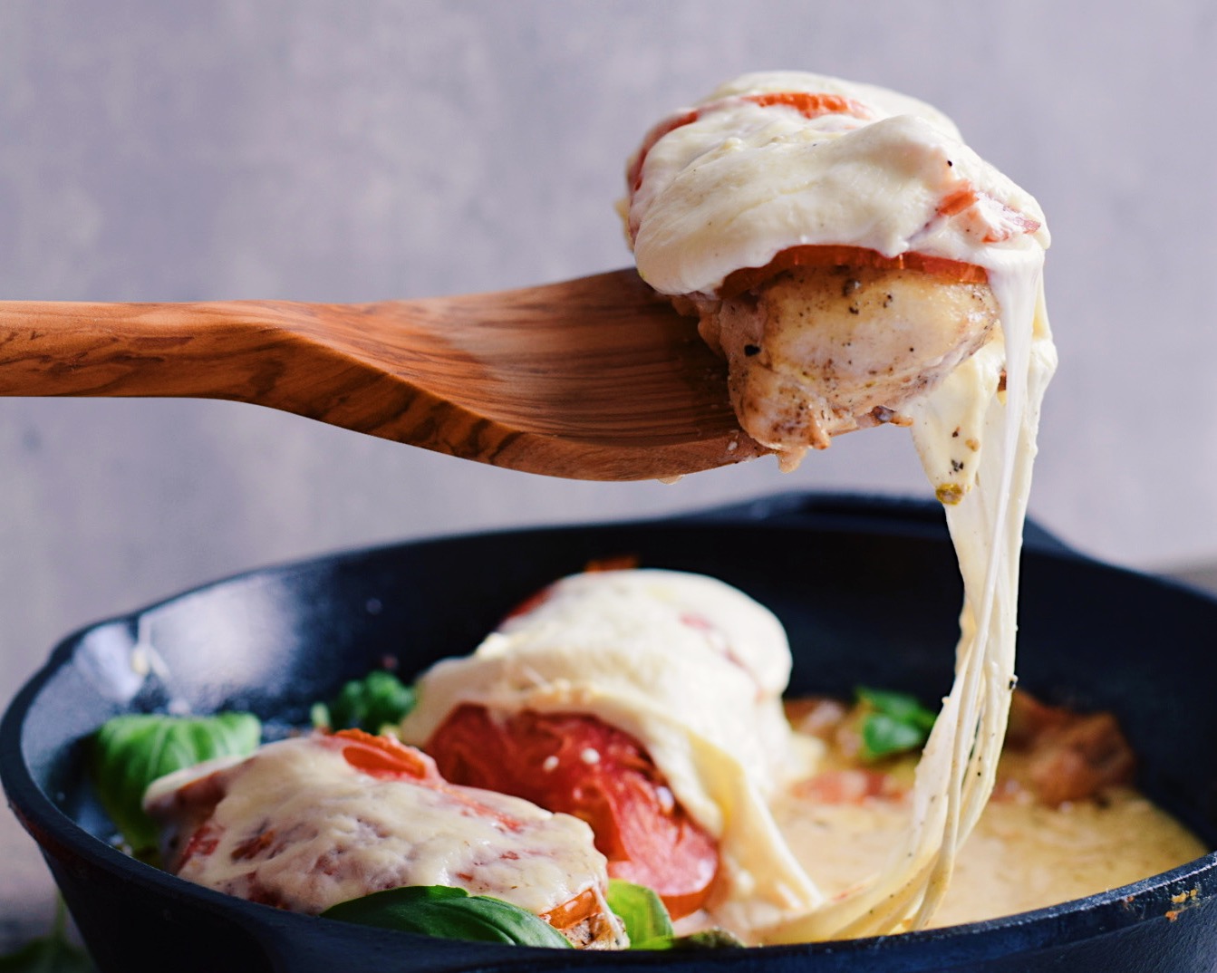 caprese chicken on a spatula over a skillet